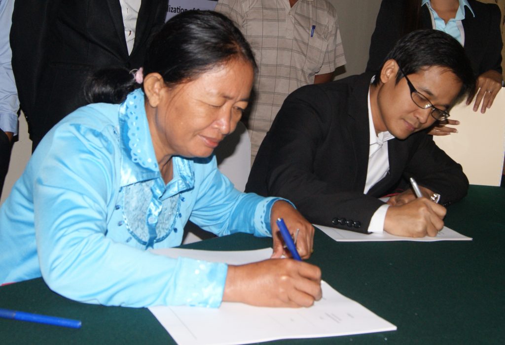 Die Vorsitzende einer Bauerngenossenschaft und AMRU-Geschäftsführer Song Saran unterzeichnen einen Vertrag © Winfried Scheewe