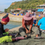 Arbeitsmigrant*innen nähen ein Fischernetz zusammen © Central