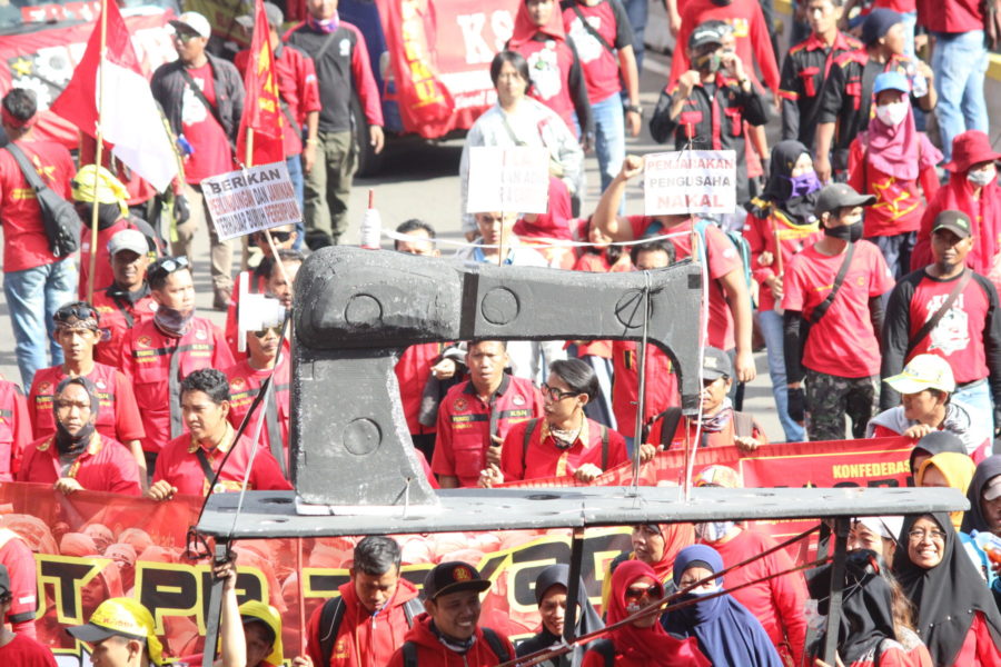 Eine riesige Nähmaschine, die von Gerakan Buruh untuk Rakyat (Gebrak – Arbeiterbewegung für das Volk) in der 1. Mai-Demonstration in Jakarta getragen wird. Die Nähmaschine symbolisiert die Produktionsmittel der Arbeiter*innen v.a. in der Bekleidungsindustrie, wo die Ausbeutung sehr hoch ist. © Dina Septi Utami/LIPS